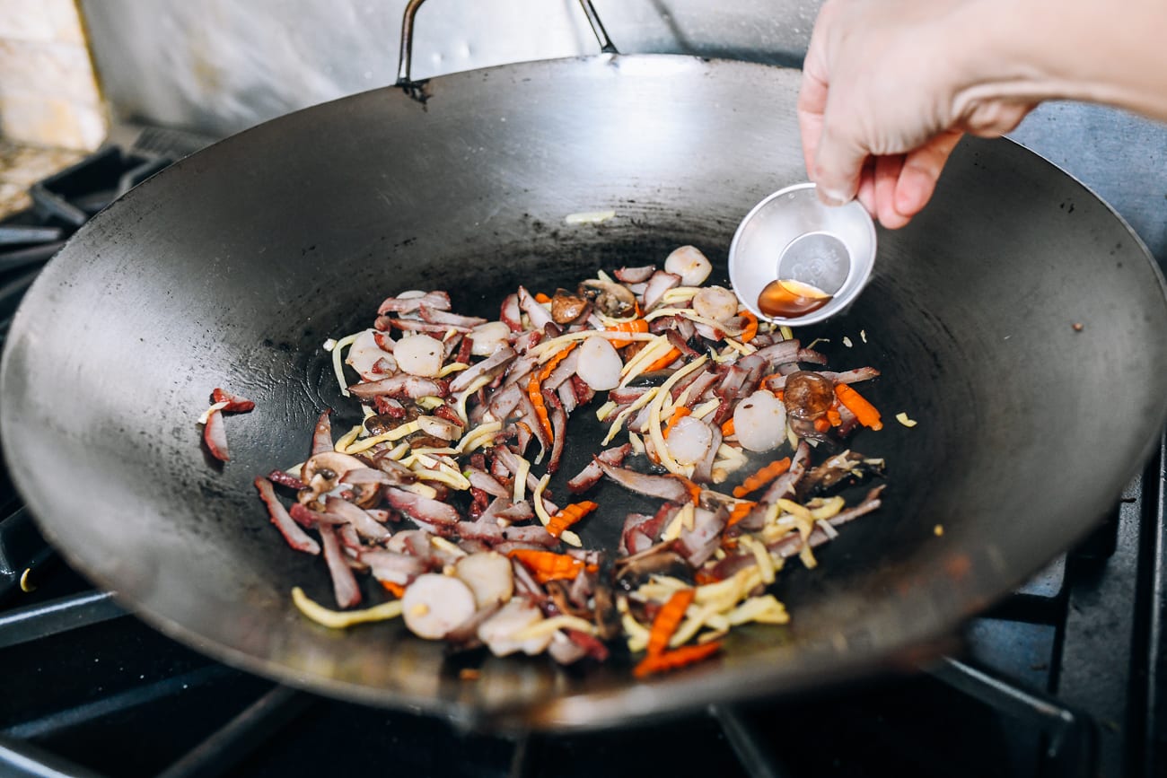Adding Shaoxing wine to roast pork and vegetables in wok