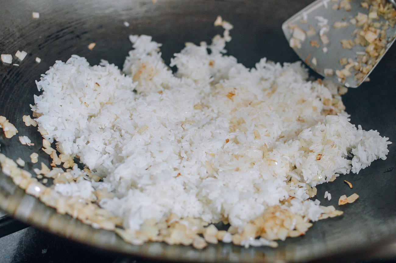Adding rice to onions in wok to make fried rice
