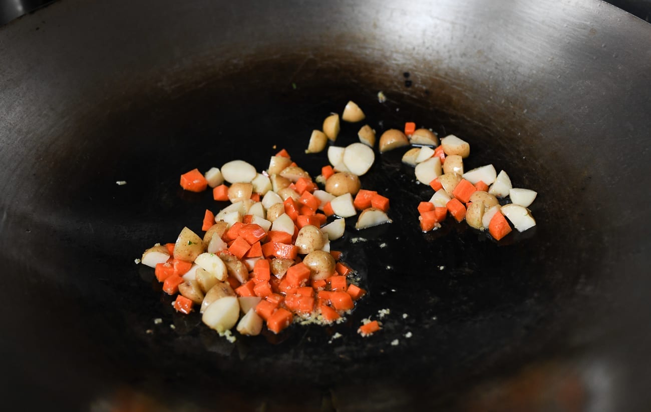 Cooking diced carrots and potatoes in wok