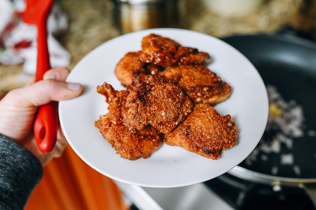 Removing crispy pan-fried chicken to a plate