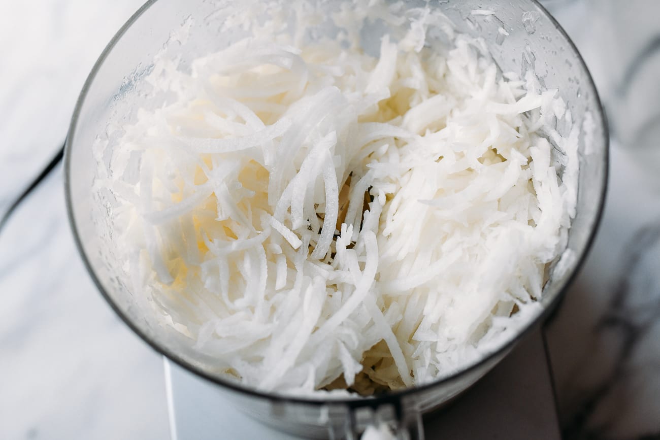 Shredded daikon radish in bowl of food processor