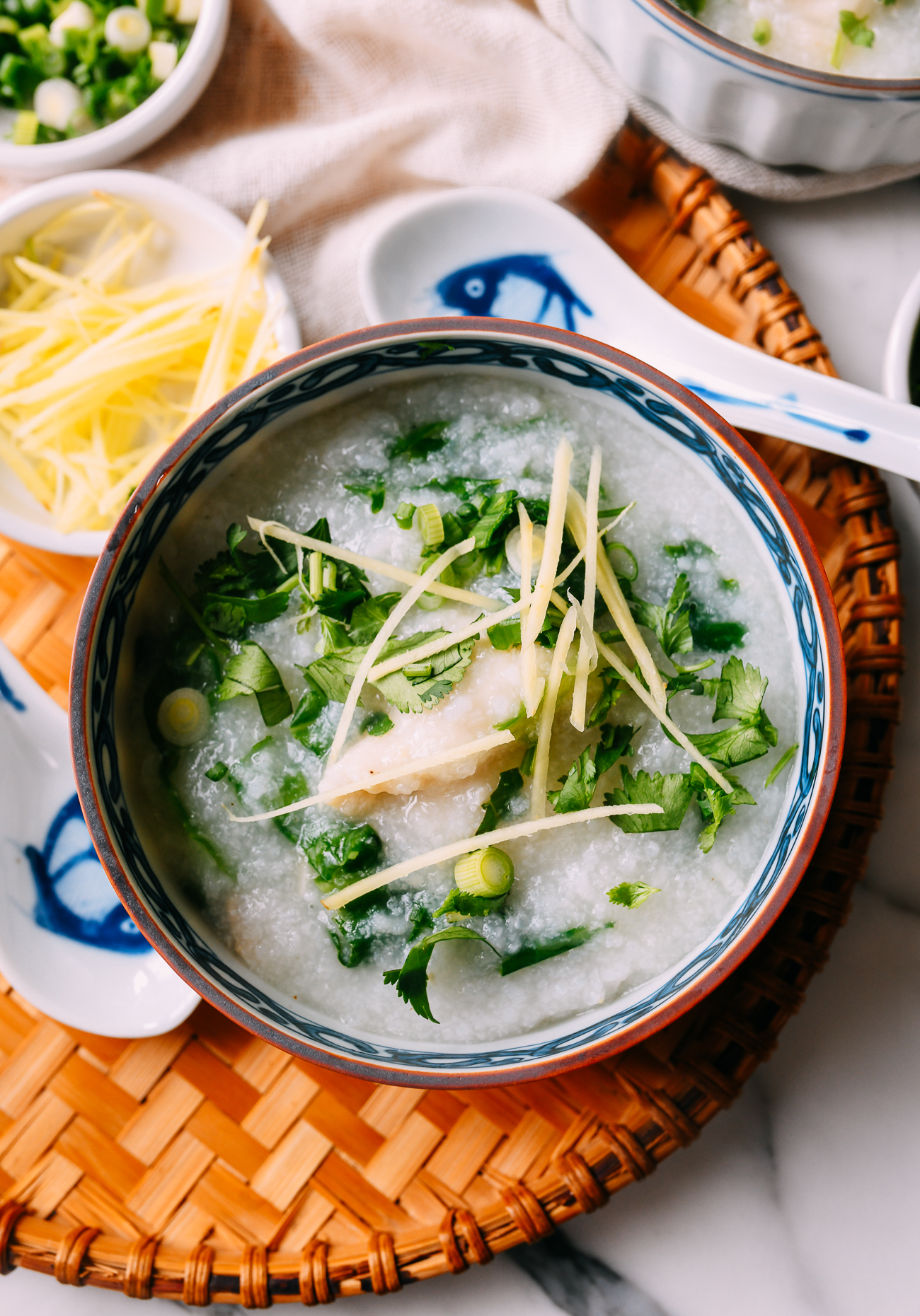 Bowl of fish congee with scallions, ginger, and cilantro