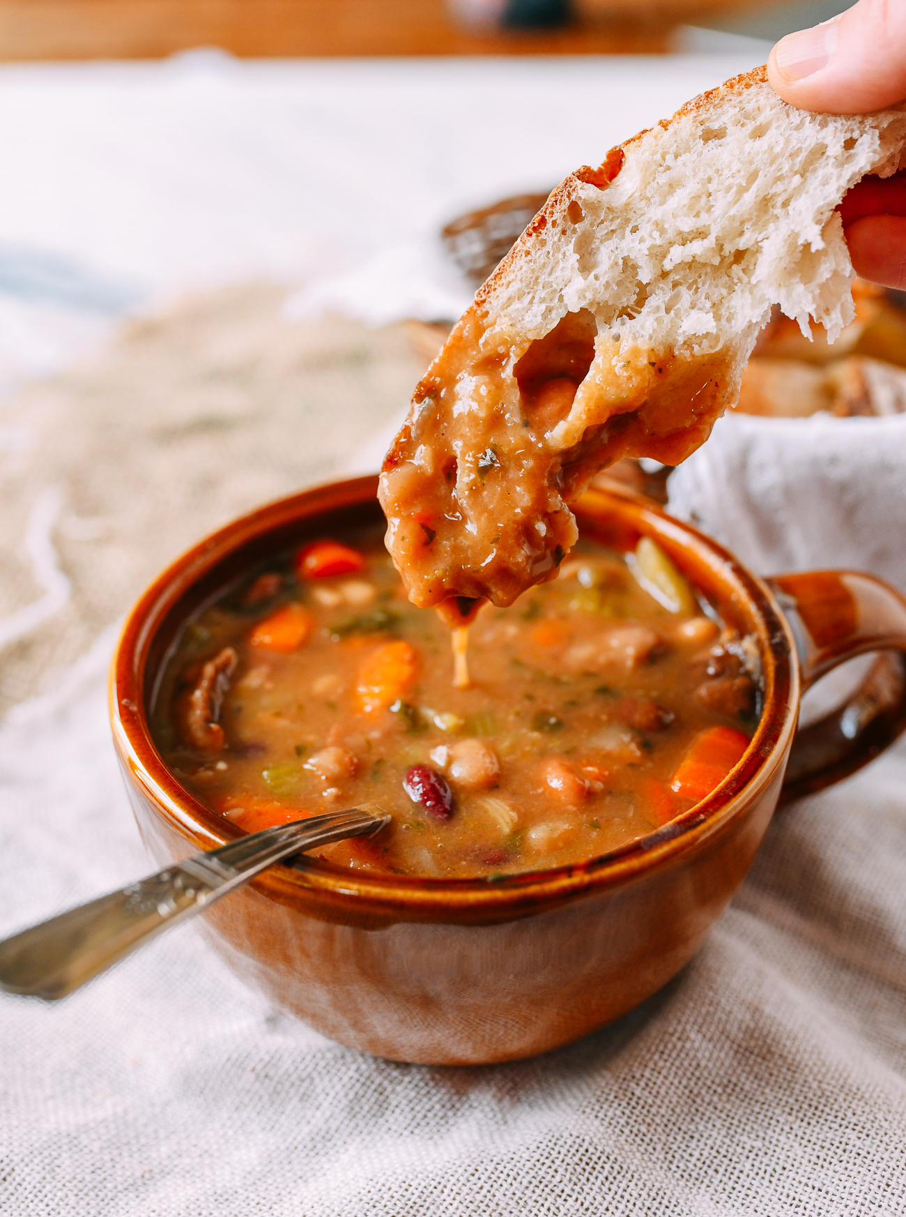 Dipping bread into ham and bean soup