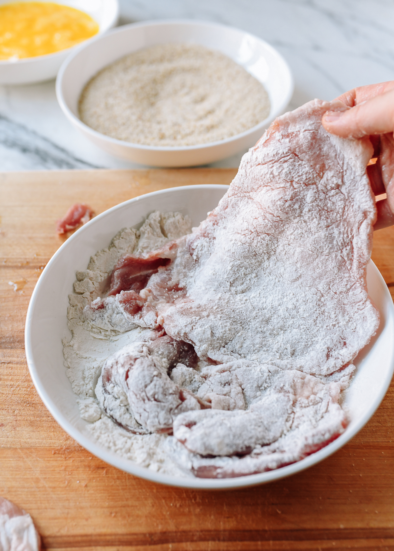 Dredging pork chop in flour