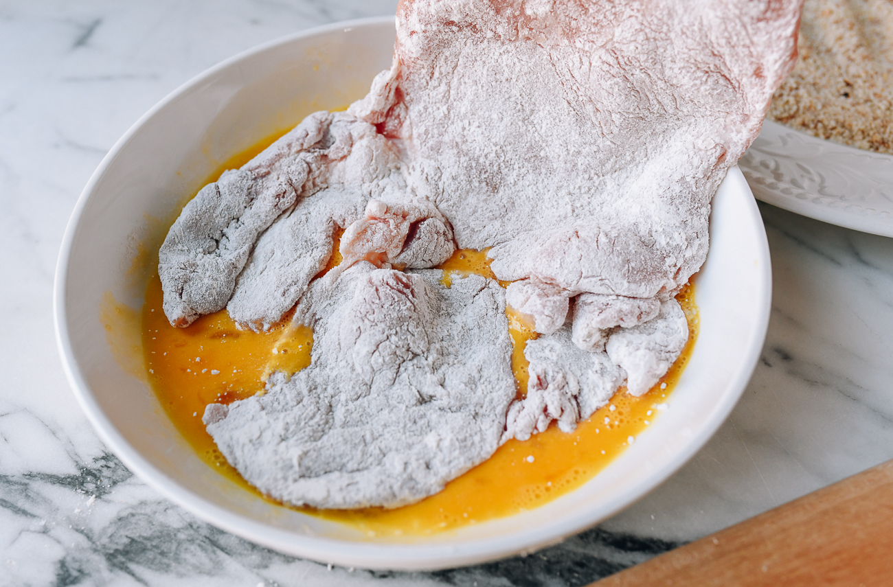 Dipping floured pork chop into egg