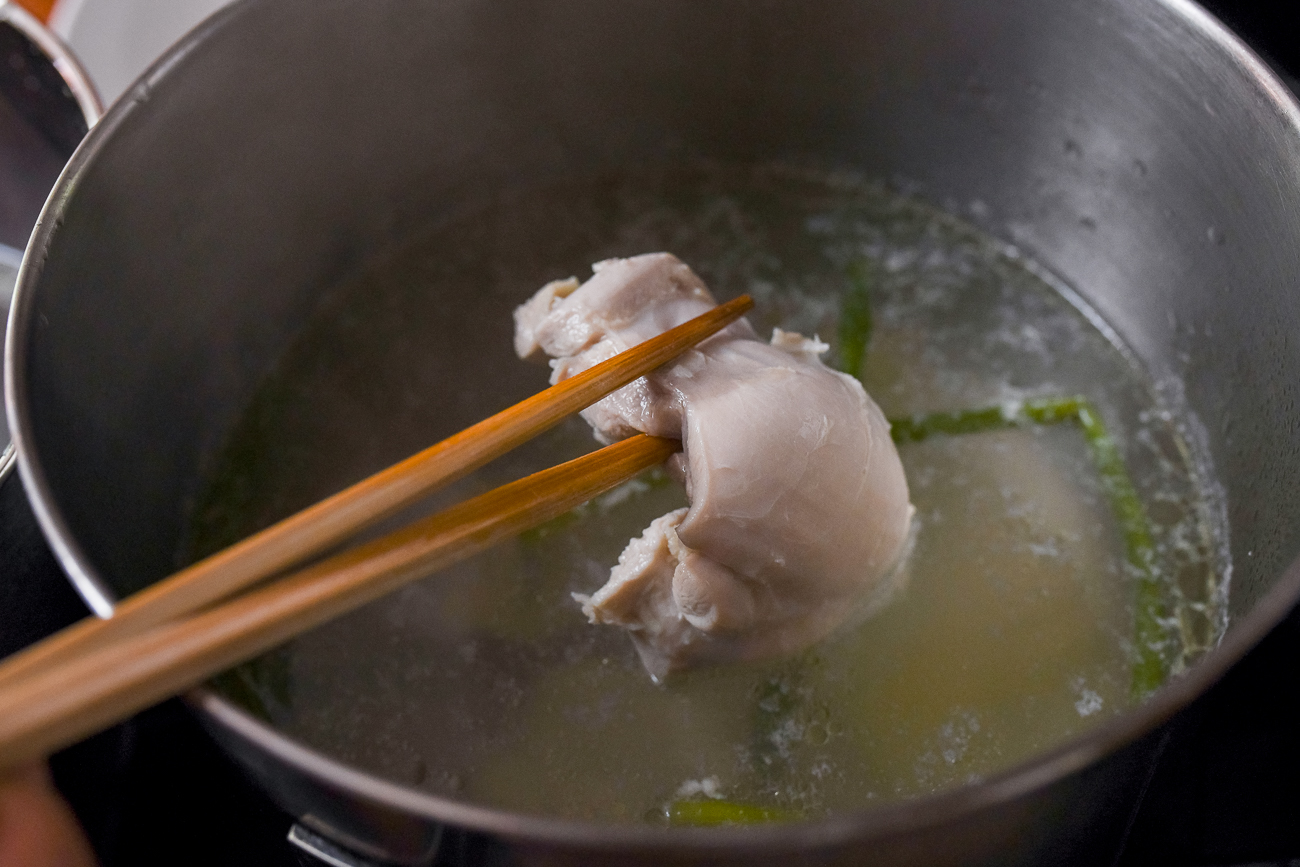 Removing poached chicken thigh from pot of water