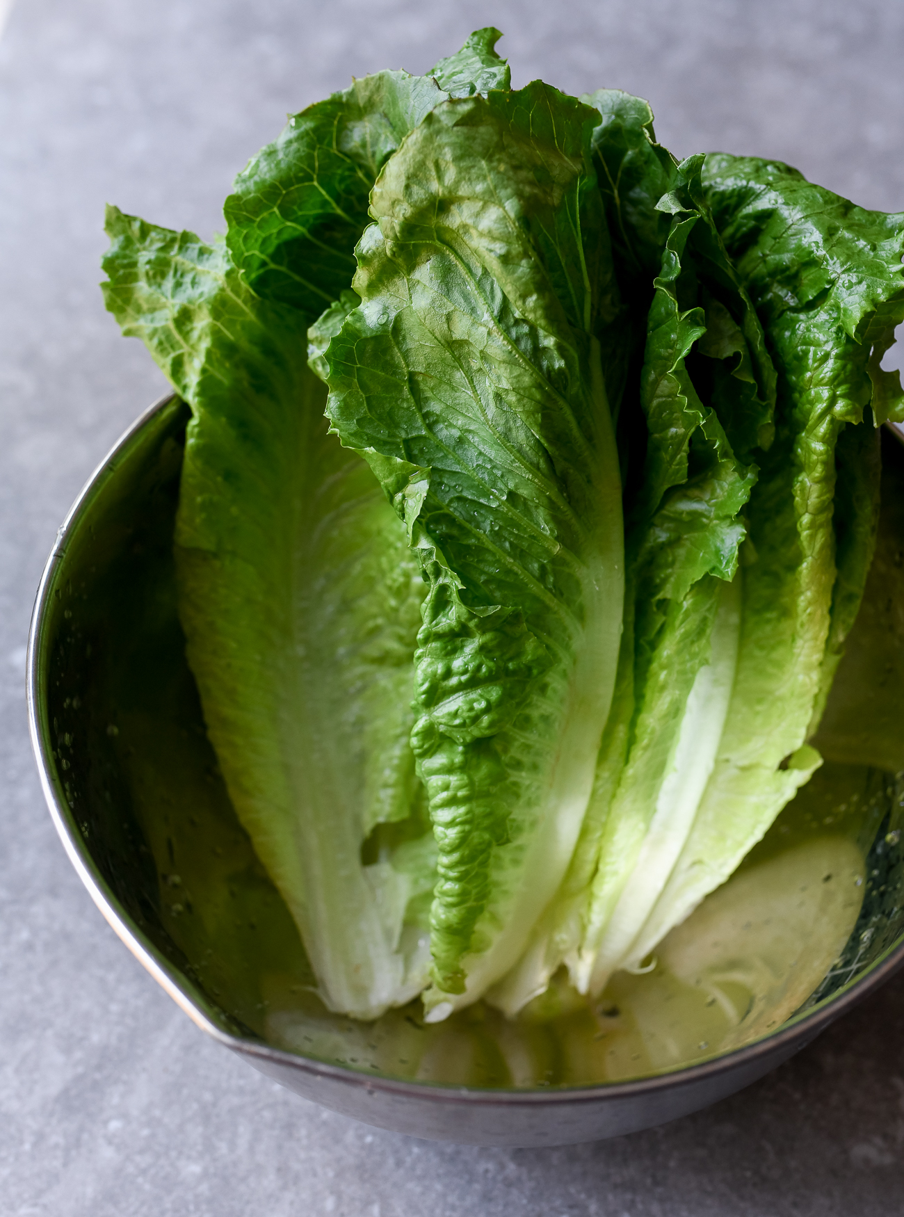 Washed romaine lettuce leaves in metal bowl