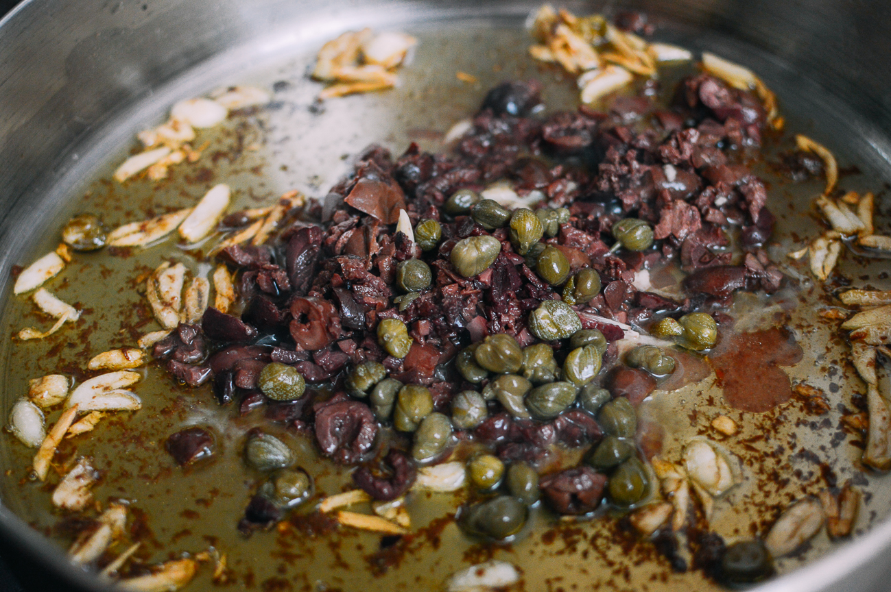 Olives, capers, anchovies, and garlic in olive oil in pan