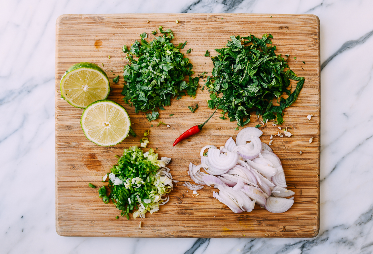Lime, mint, cilantro, scallions, shallots and chili on cutting board