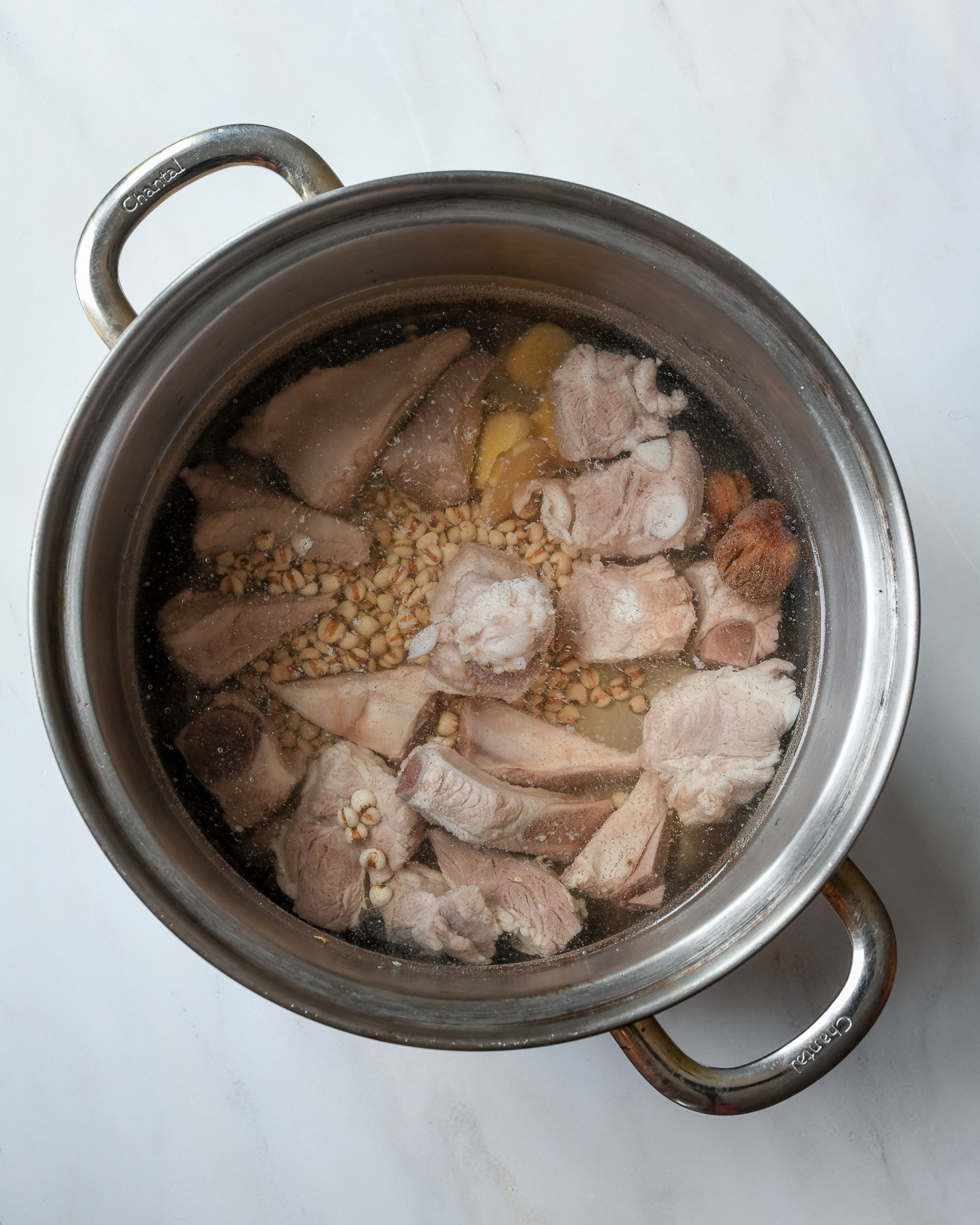 Blanched pork bones with barley, ginger, and dates in soup pot