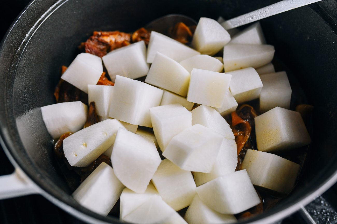 Adding chunks of daikon radish to the stew