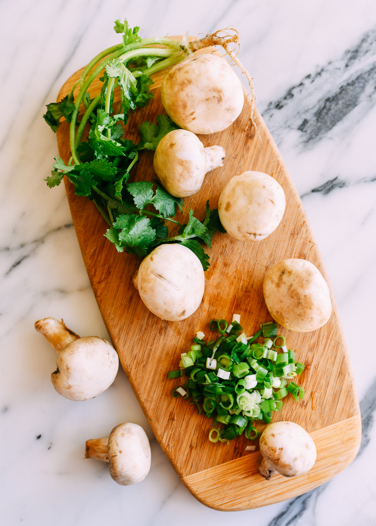 White button mushrooms and herbs on cutting board