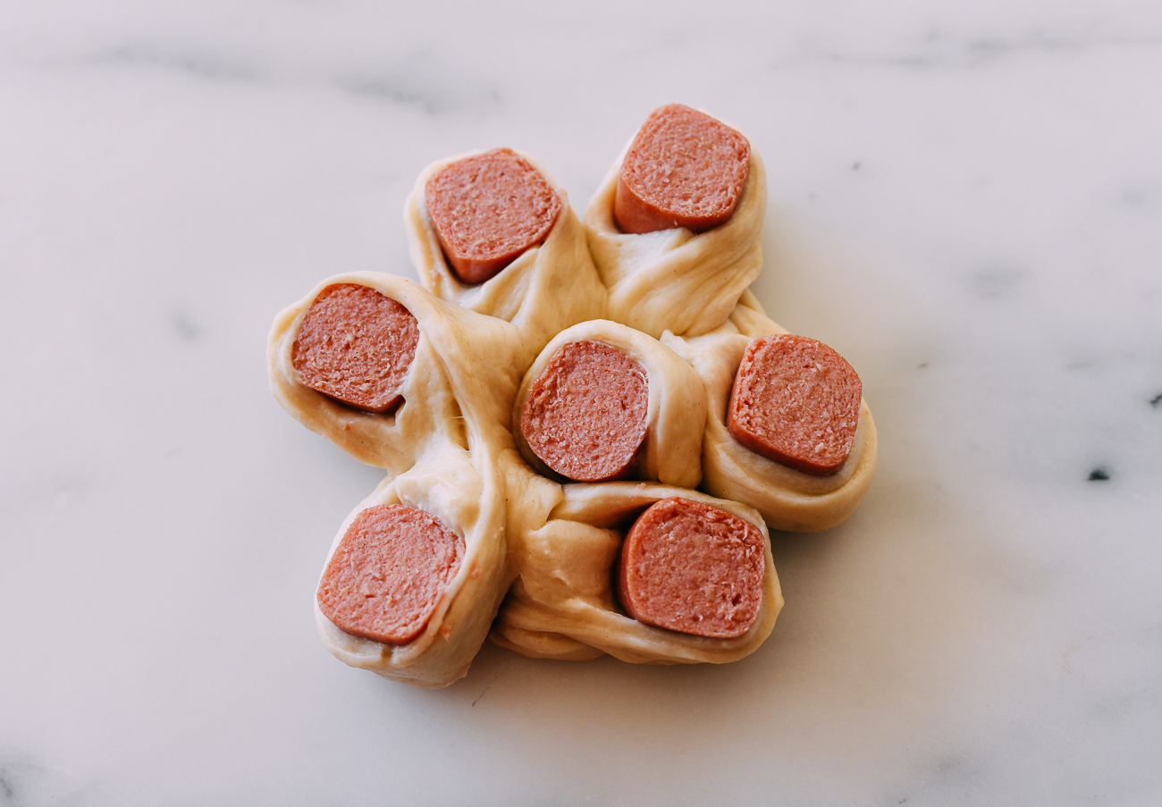 Raw dough arranged into flower hot dog bun shape