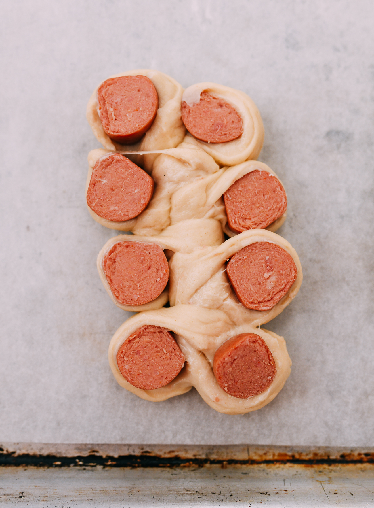 hot dog pieces cut side up on either side of uncut piece of dough