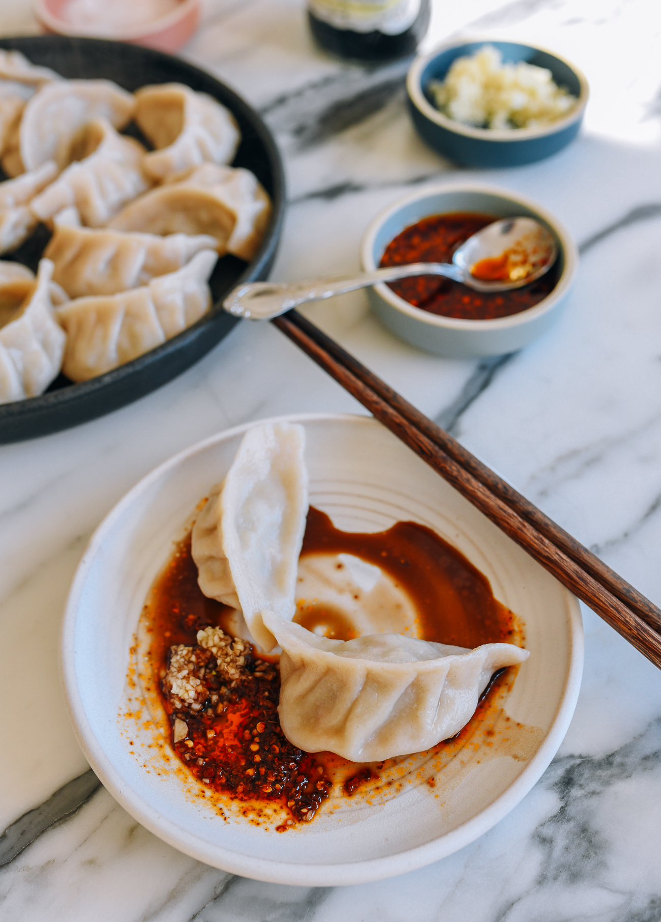 Pork and Celery Dumplings on plate with chili oil, garlic, and vinegar