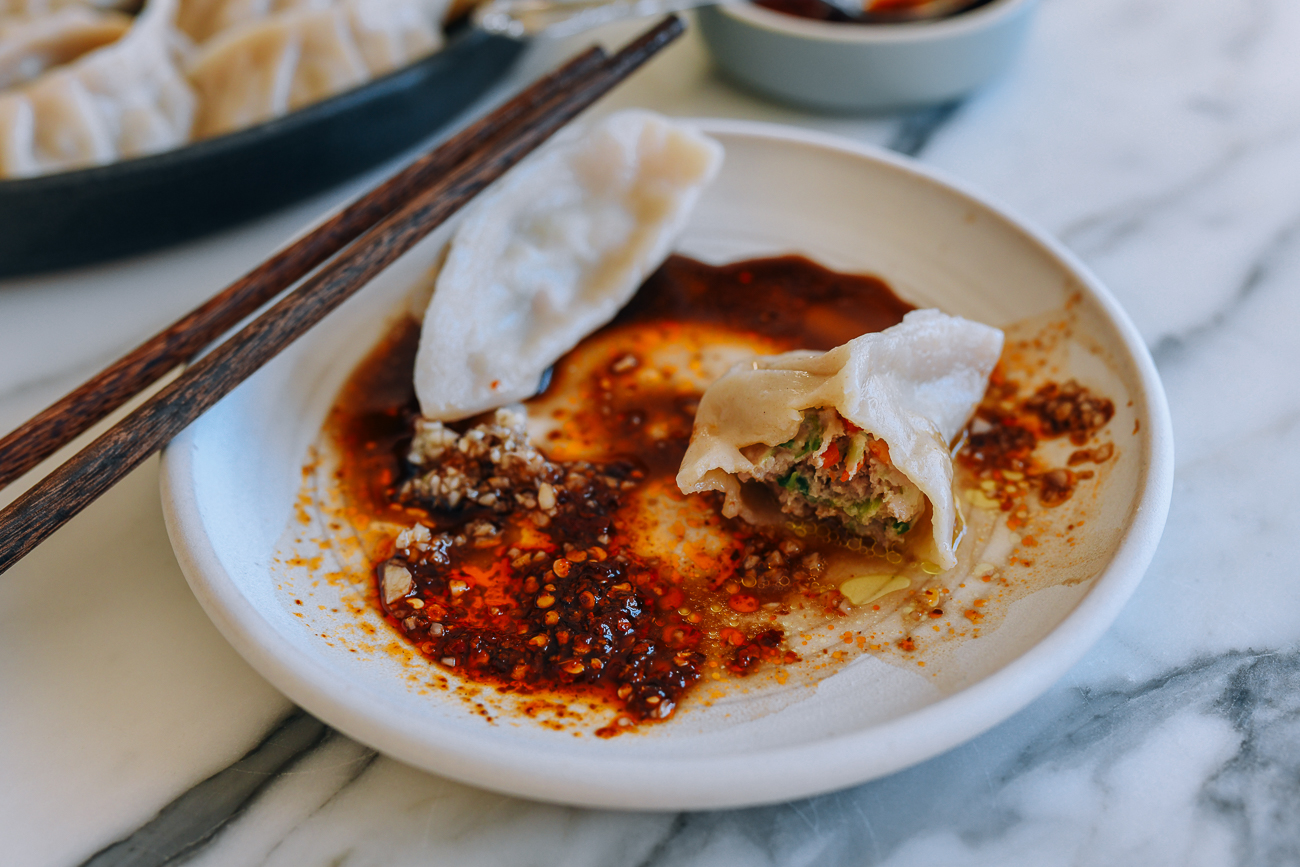 Chinese Pork and Celery Dumplings on plate with vinegar, chili oil, and minced garlic