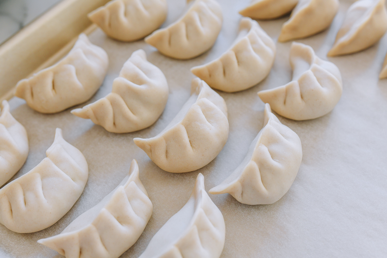 Assembled dumplings on parchment-lined tray