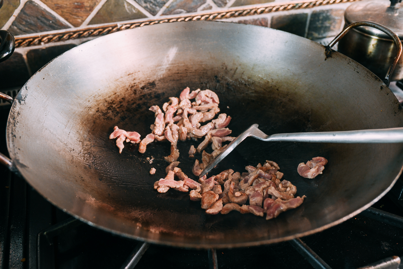 Stir-frying thin strips of pork in wok