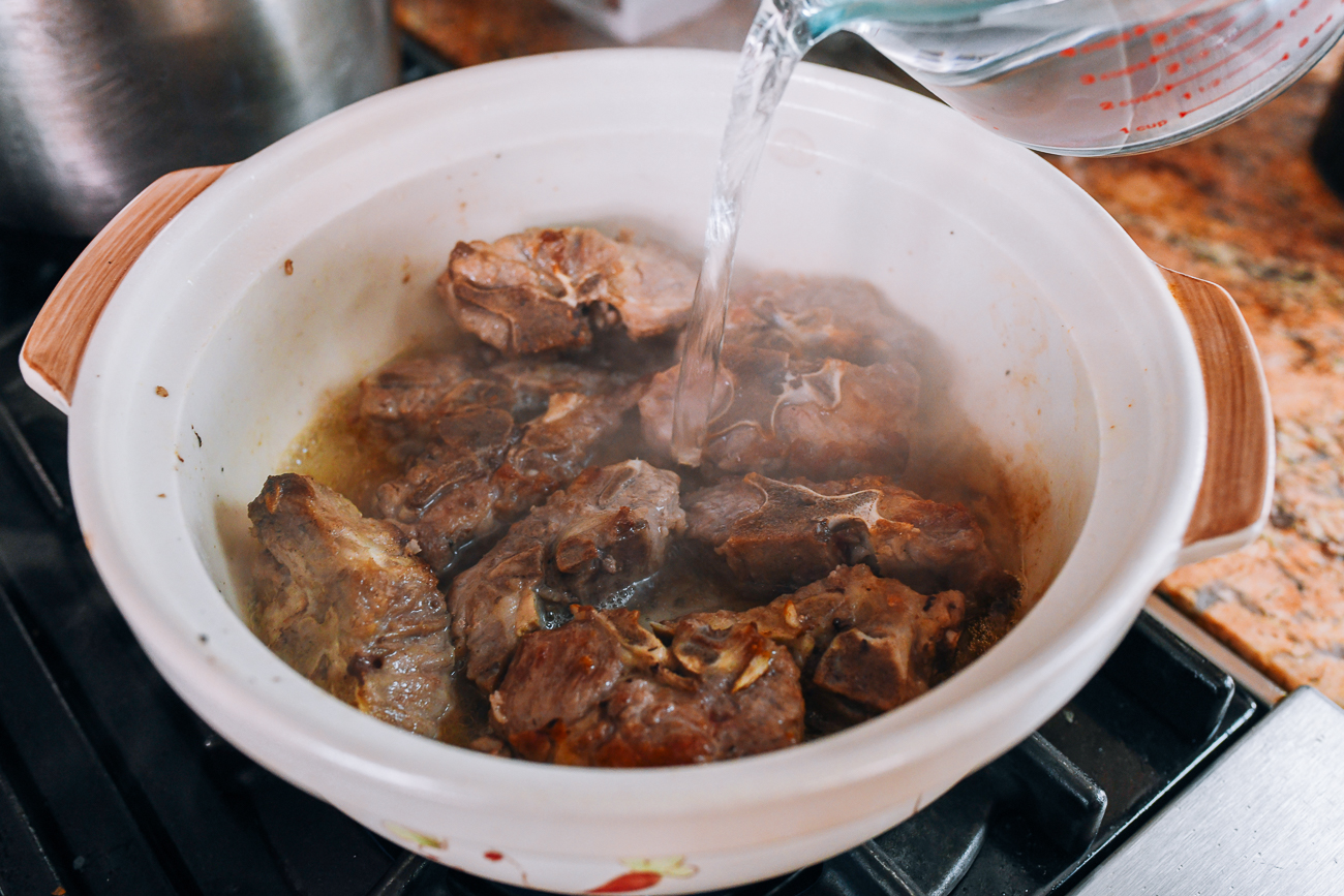 Pouring boiling water over seared pork neck bones