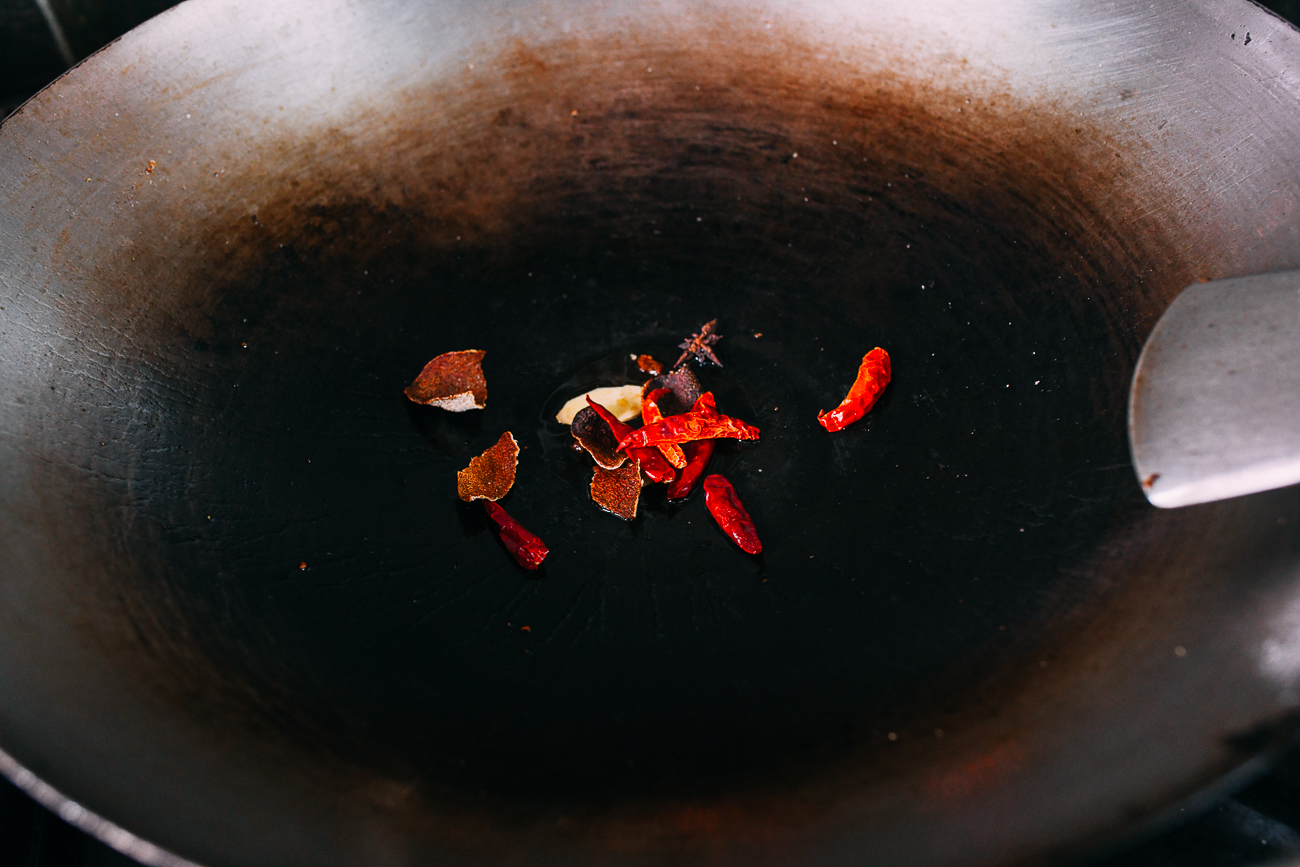 Ginger, dried orange peel, dried chilies, and star anise in wok