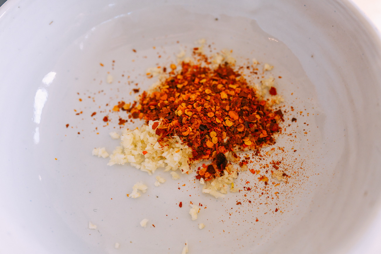 Minced garlic and sichuan chili flakes in white bowl
