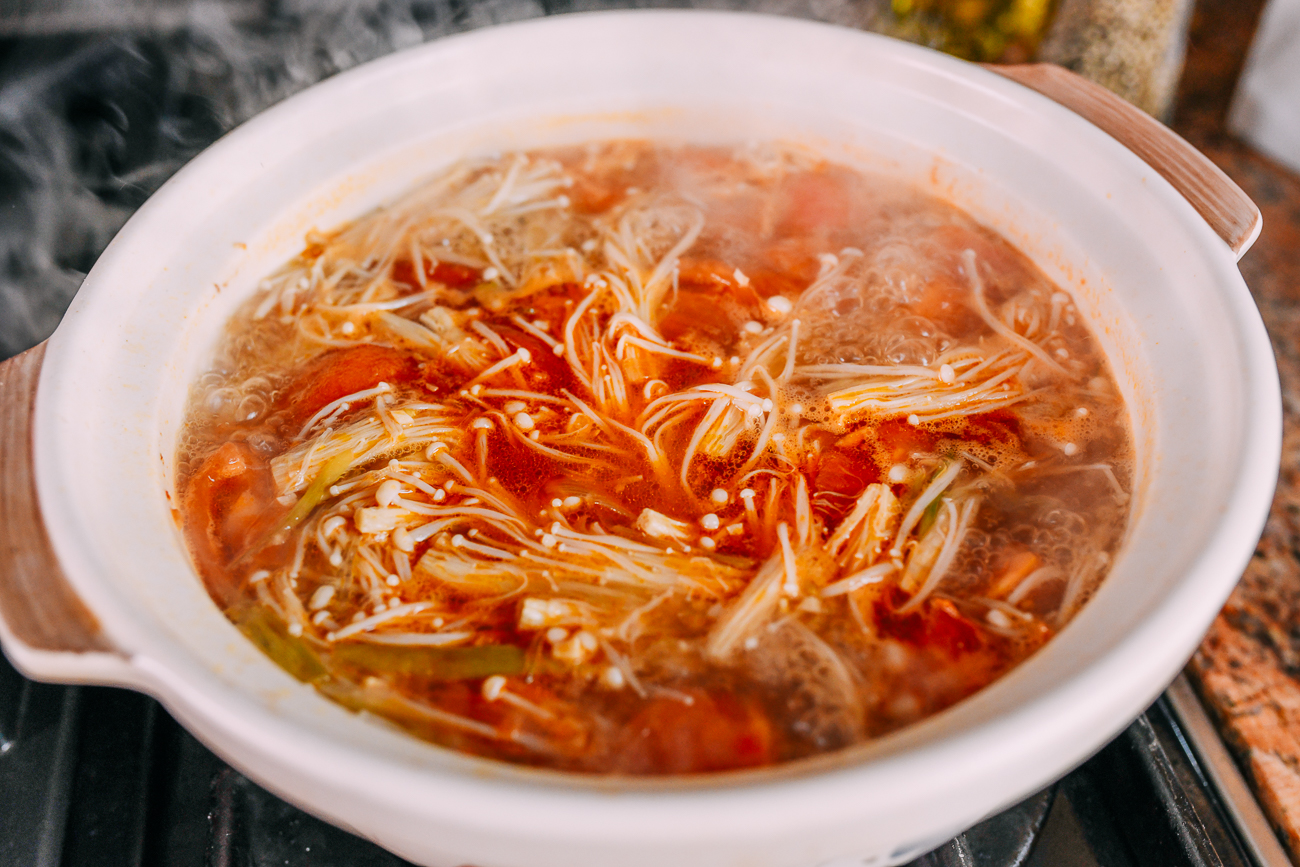 Simmering broth with tomato, enoki, and mung bean noodles