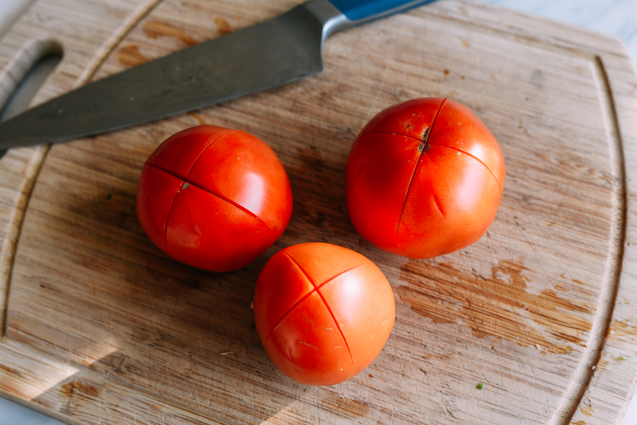 X's cut into the bottom of three tomatoes