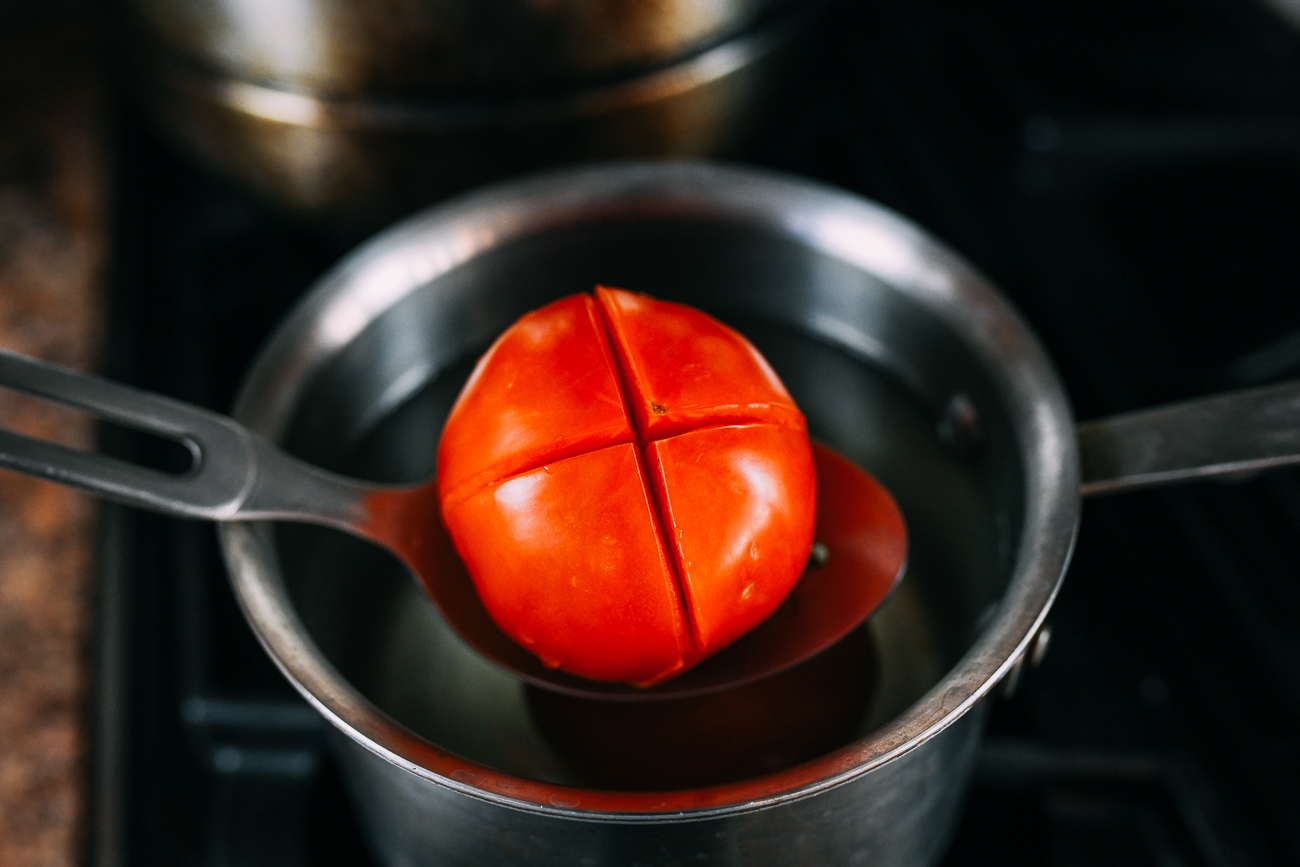 Blanching tomato with X cut into the bottom