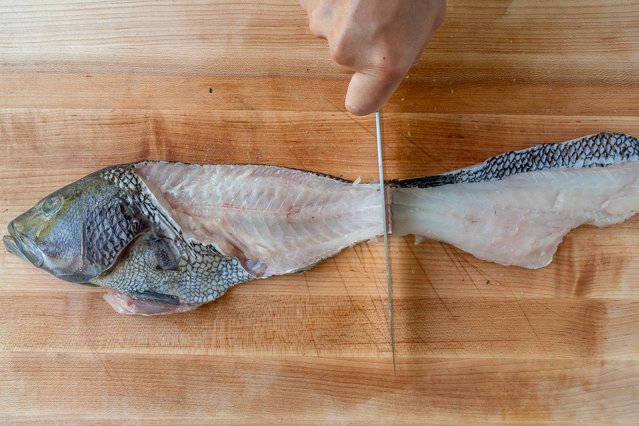 cutting fish at the tail to separate fillets