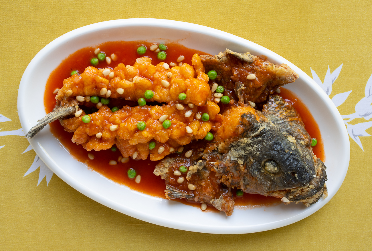 Squirrel fish garnished with sweet and sour sauce, pine nuts, and peas