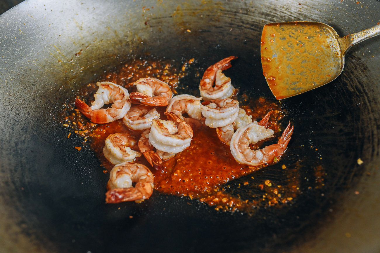 Adding seared tiger shrimp to chili garlic sauce in wok