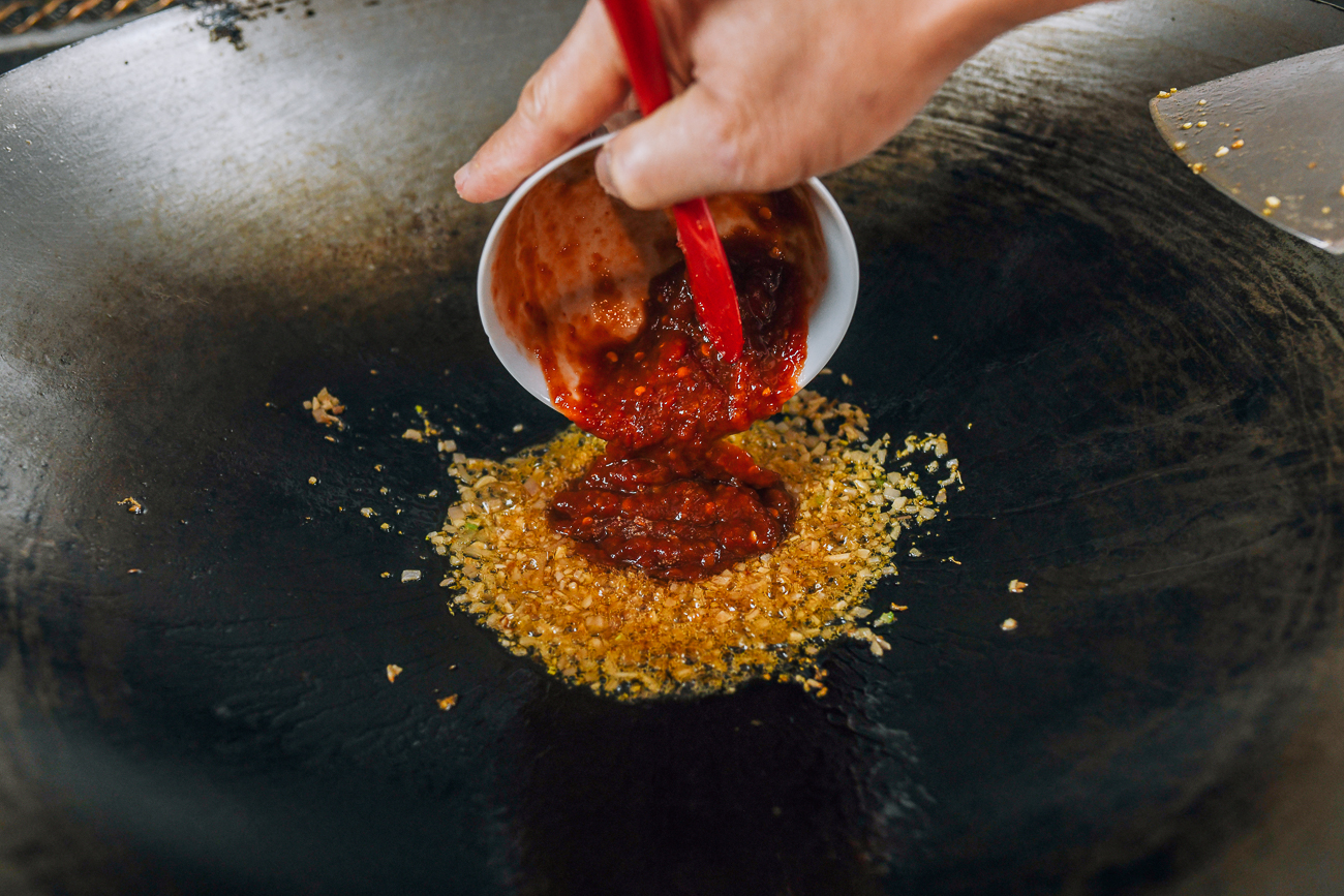 Adding chili garlic sauce mixture to wok