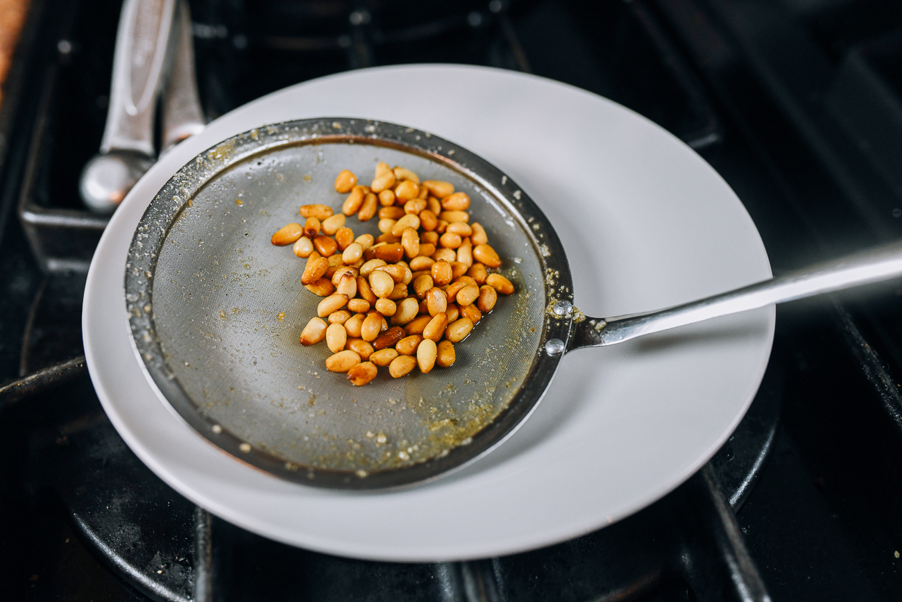 fried pine nuts in fine mesh strainer