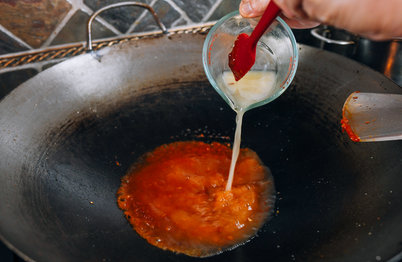 Adding vinegar mixture to sauce in wok