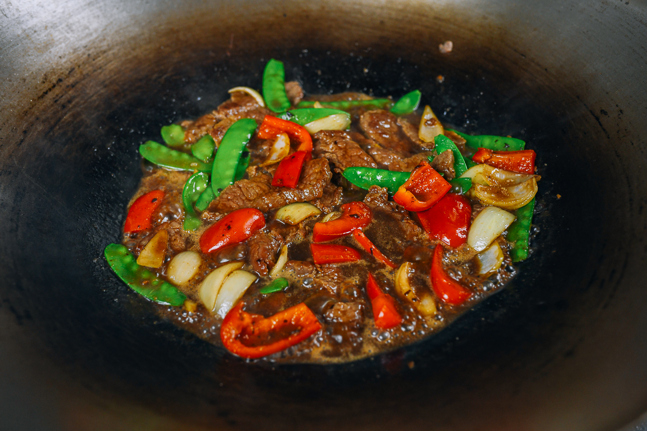 beef with black bean sauce with onions, peppers, and snow peas in wok