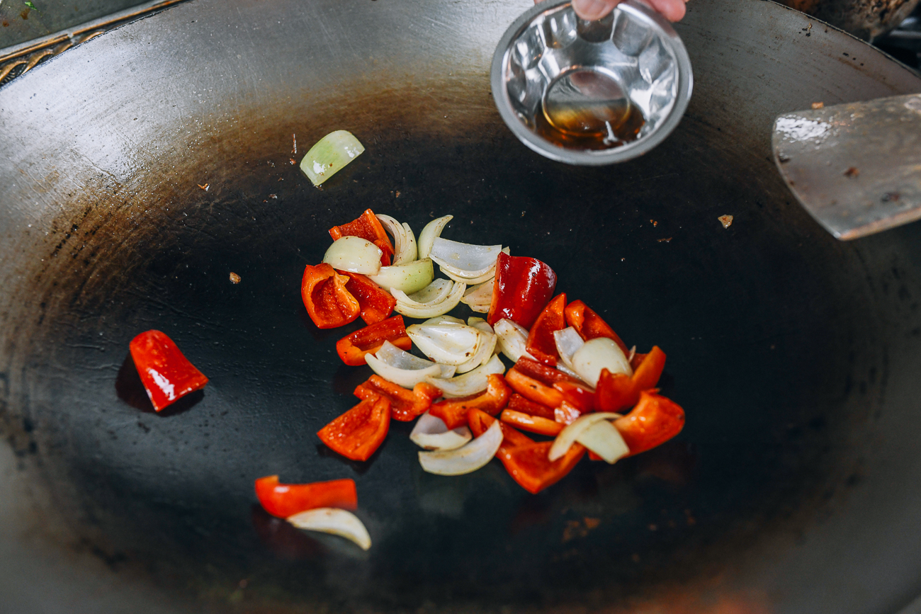 Adding Shaoxing wine to onions and peppers to deglaze wok