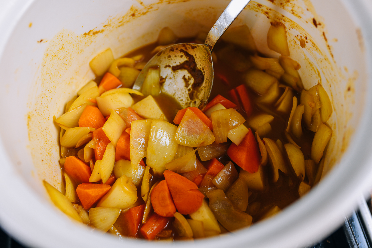 Agregar caldo a las verduras al curry