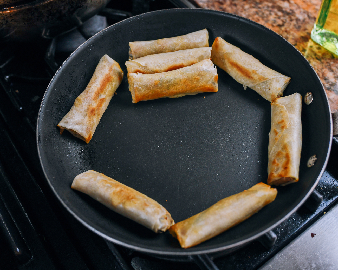browning spring rolls against the side of a pan