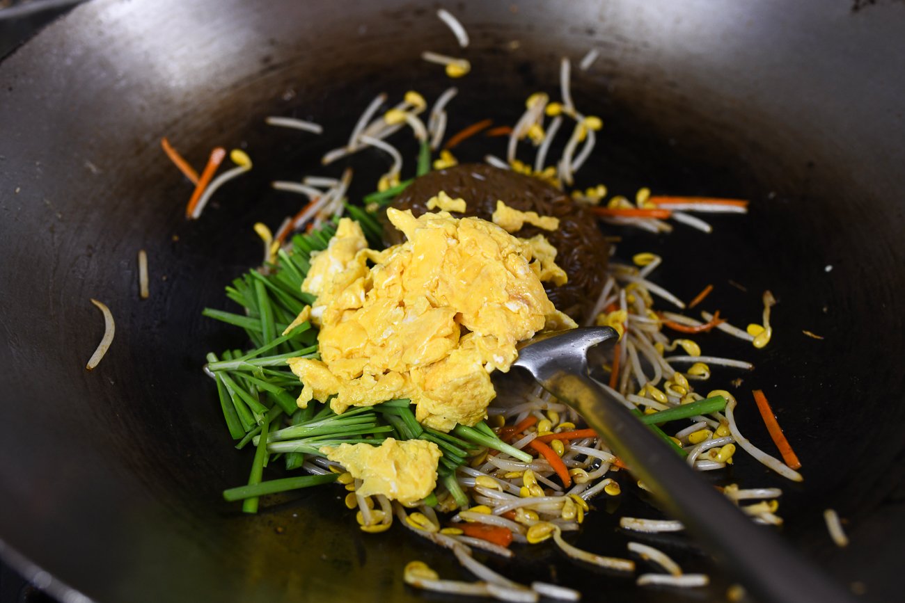 adding scrambled eggs to stir-fry