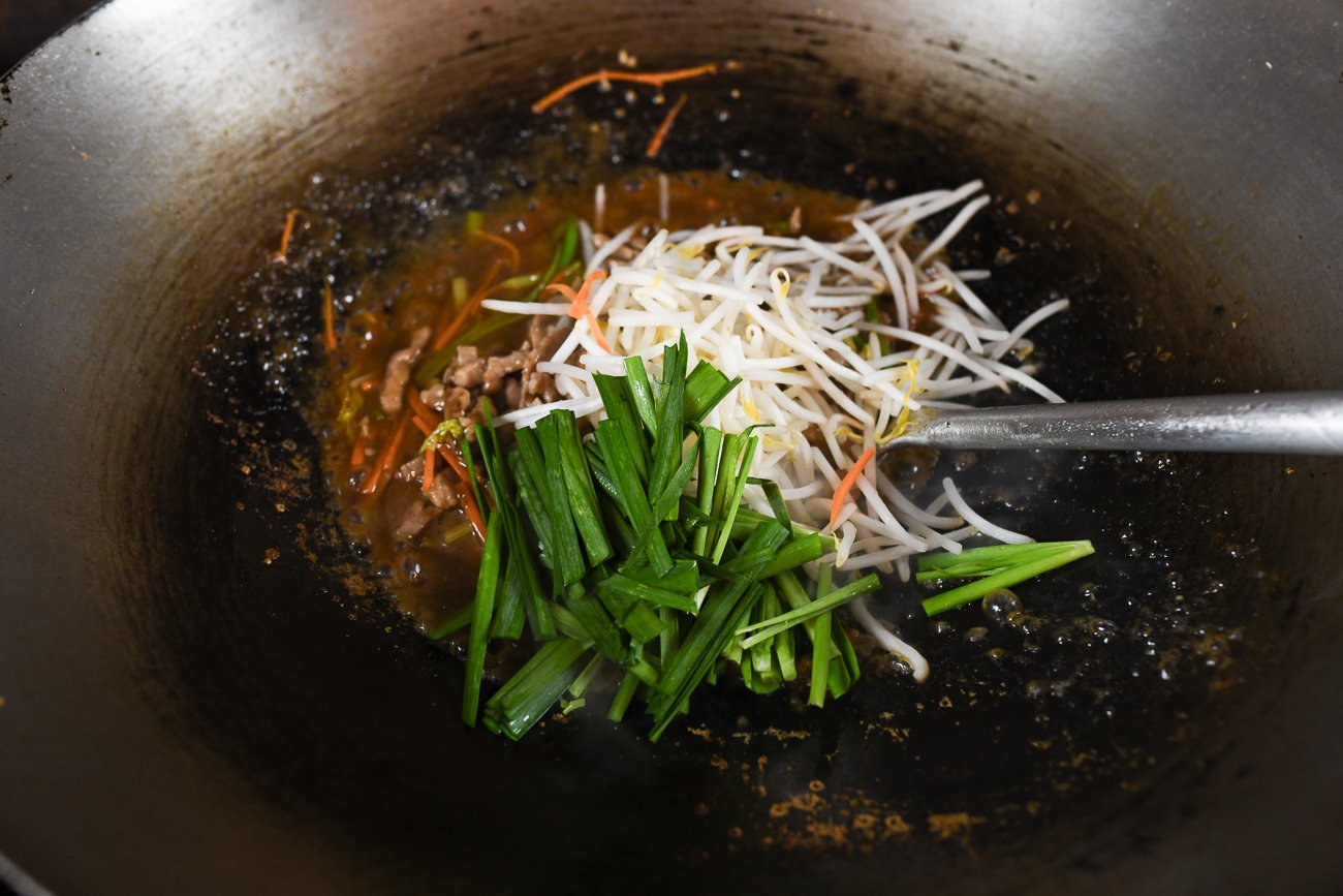 adding bean sprouts and chives to sauce