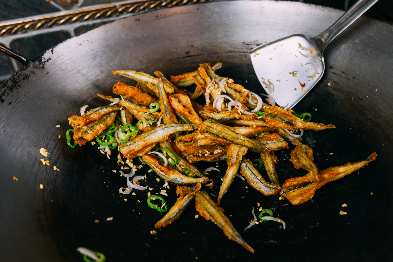 tossing smelts with aromatics and spices