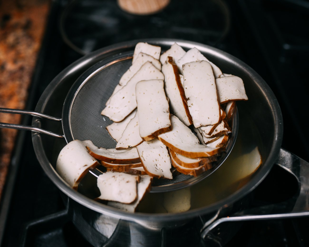 Removing blanched tofu from pot with strainer