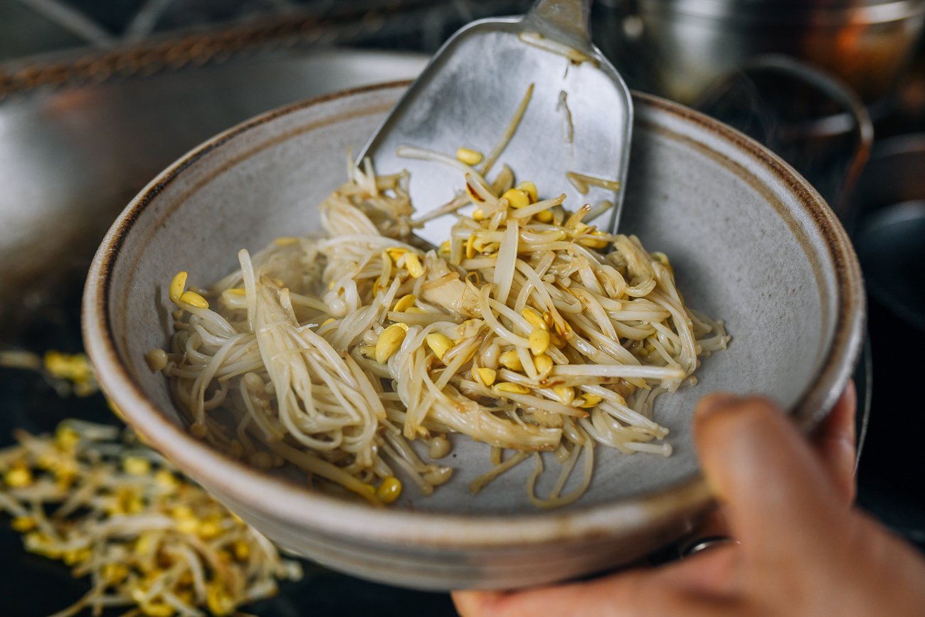 putting enoki mushrooms and bean sprouts in bottom of serving dish