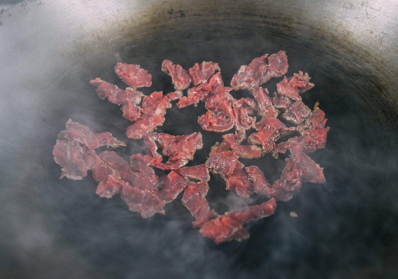 searing sliced beef in wok