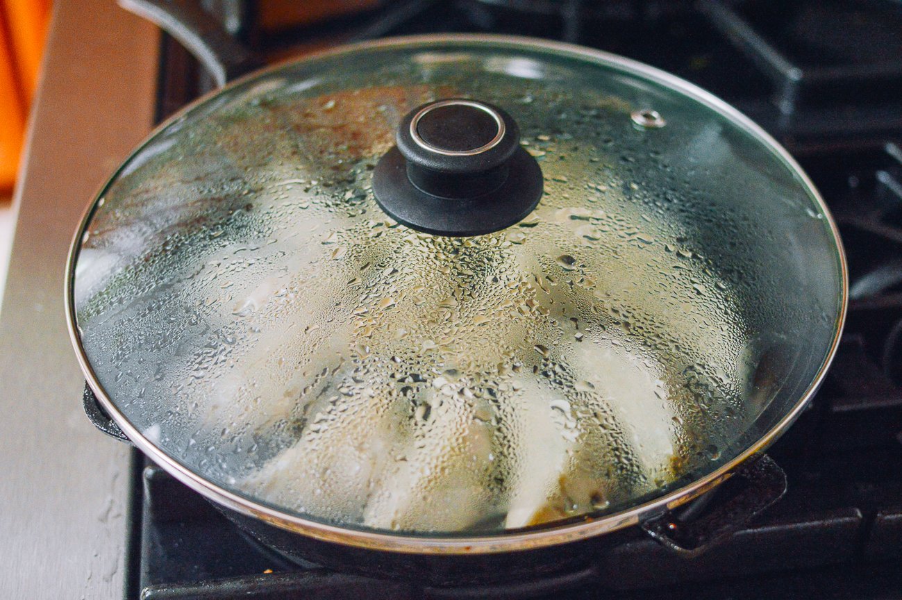 covered pan of steaming dumplings