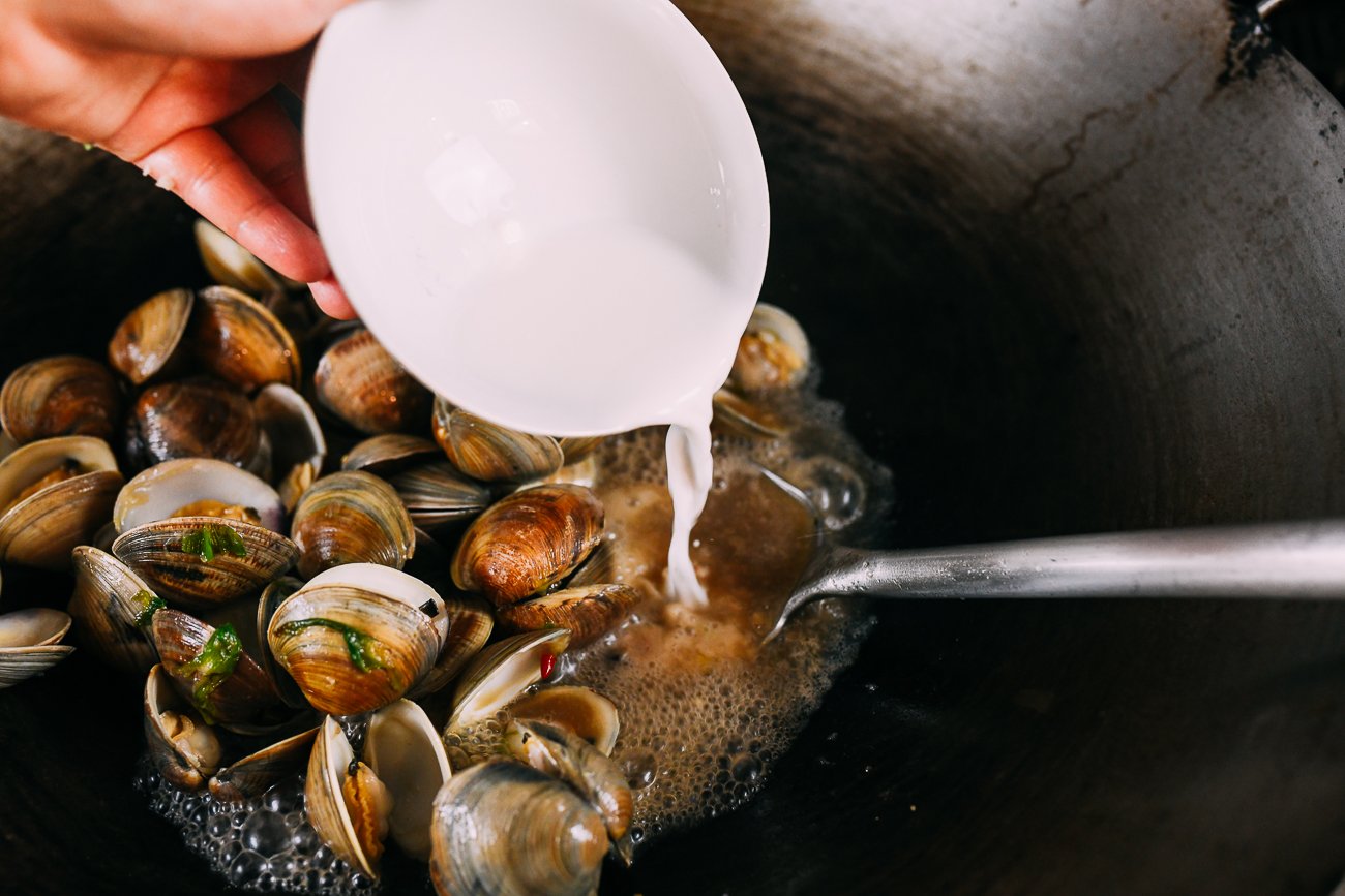 pouring cornstarch slurry in to sauce with clams