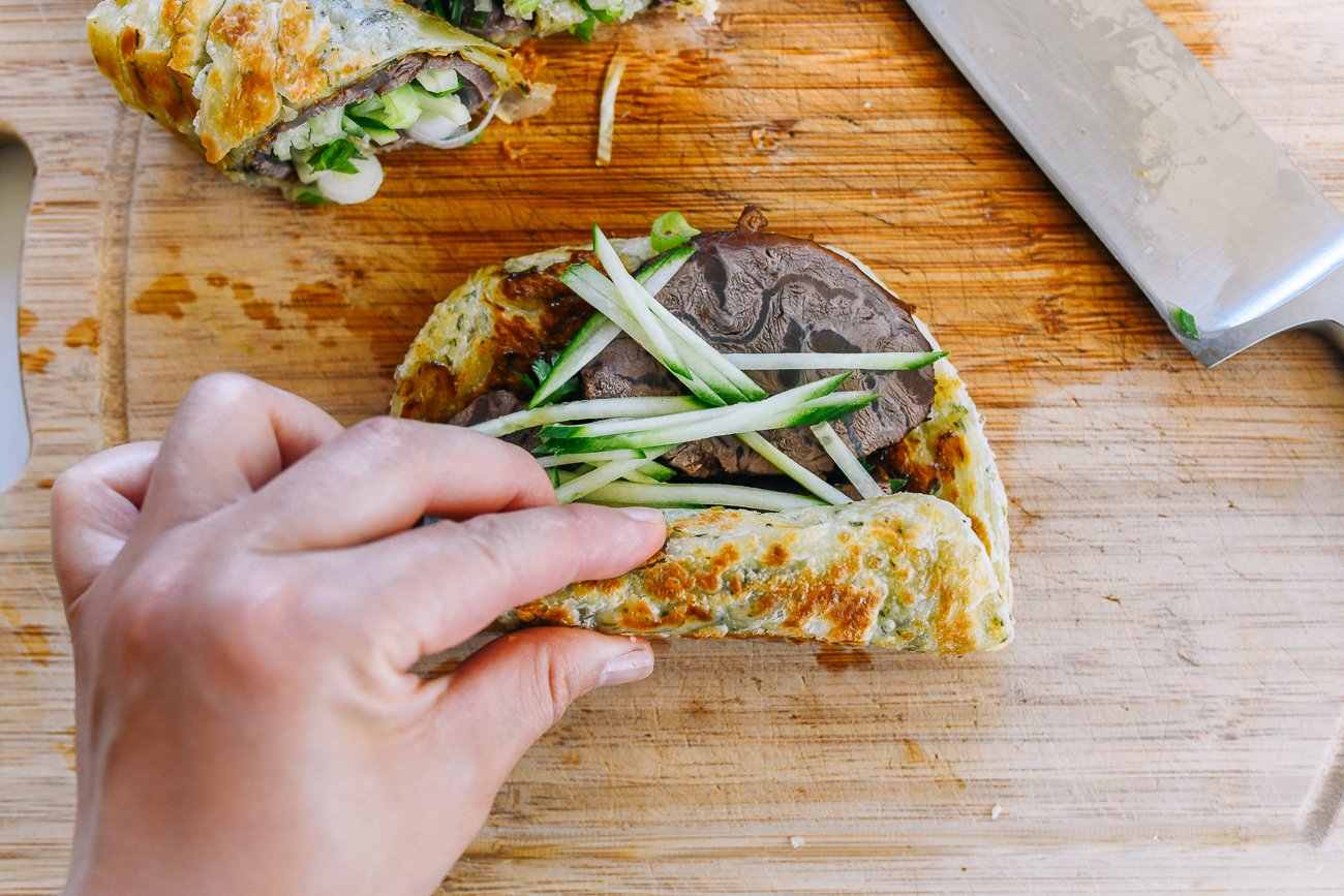 rolling beef and cucumber into scallion pancake