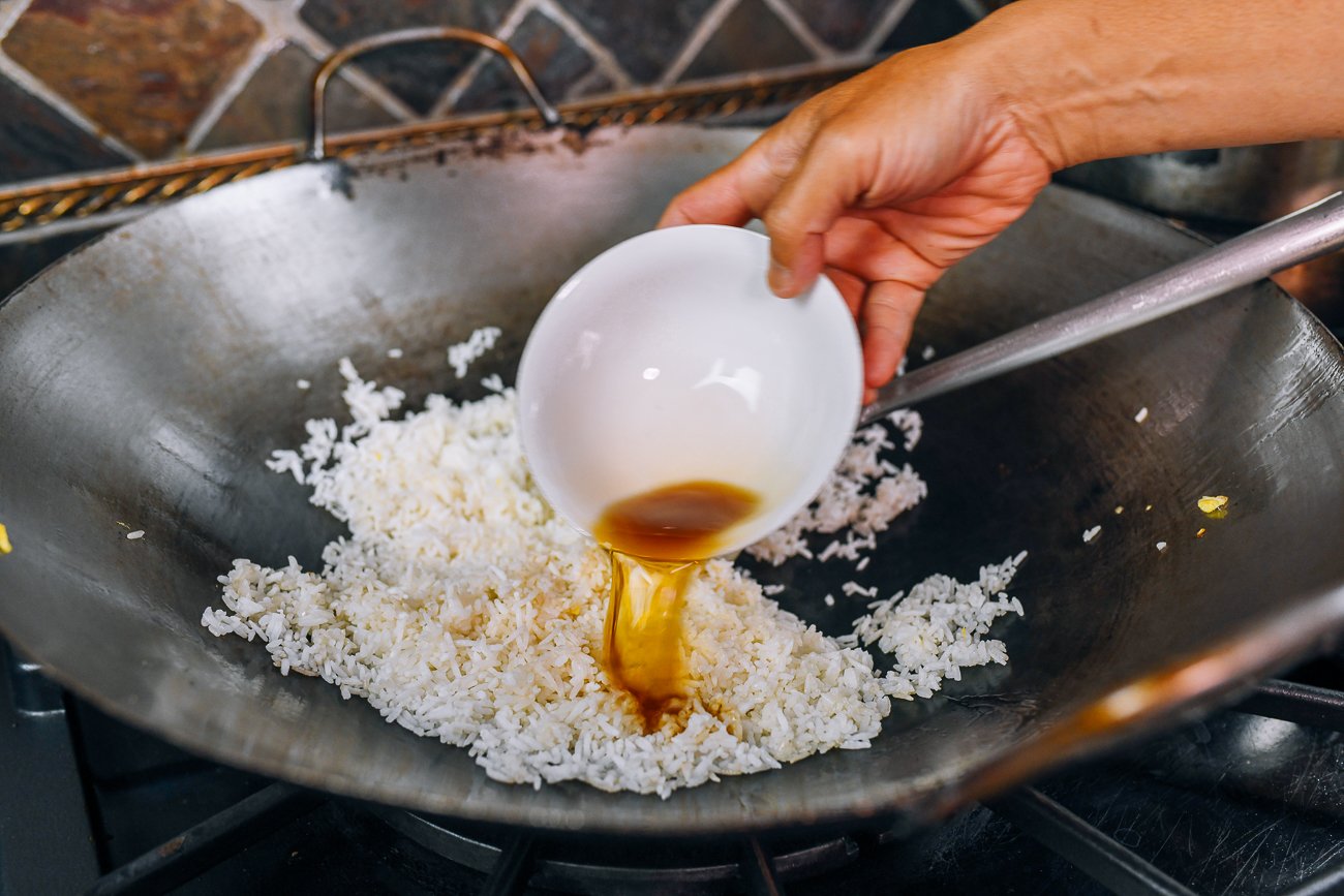 adding rice seasoning to white rice in wok