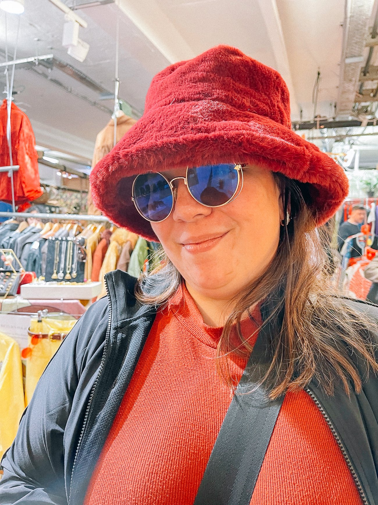 Kim wearing sunglasses and a fuzzy red bucket hat