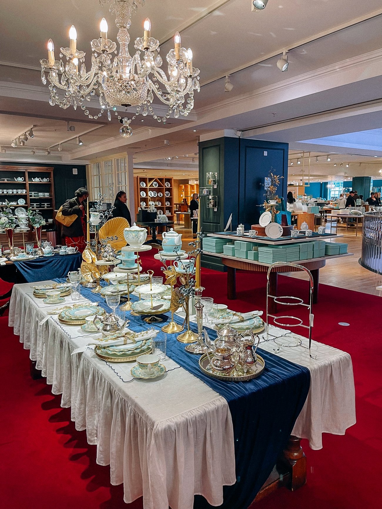 Fortnum & Mason silver set and tea set on a display table with crystal chandelier overhead